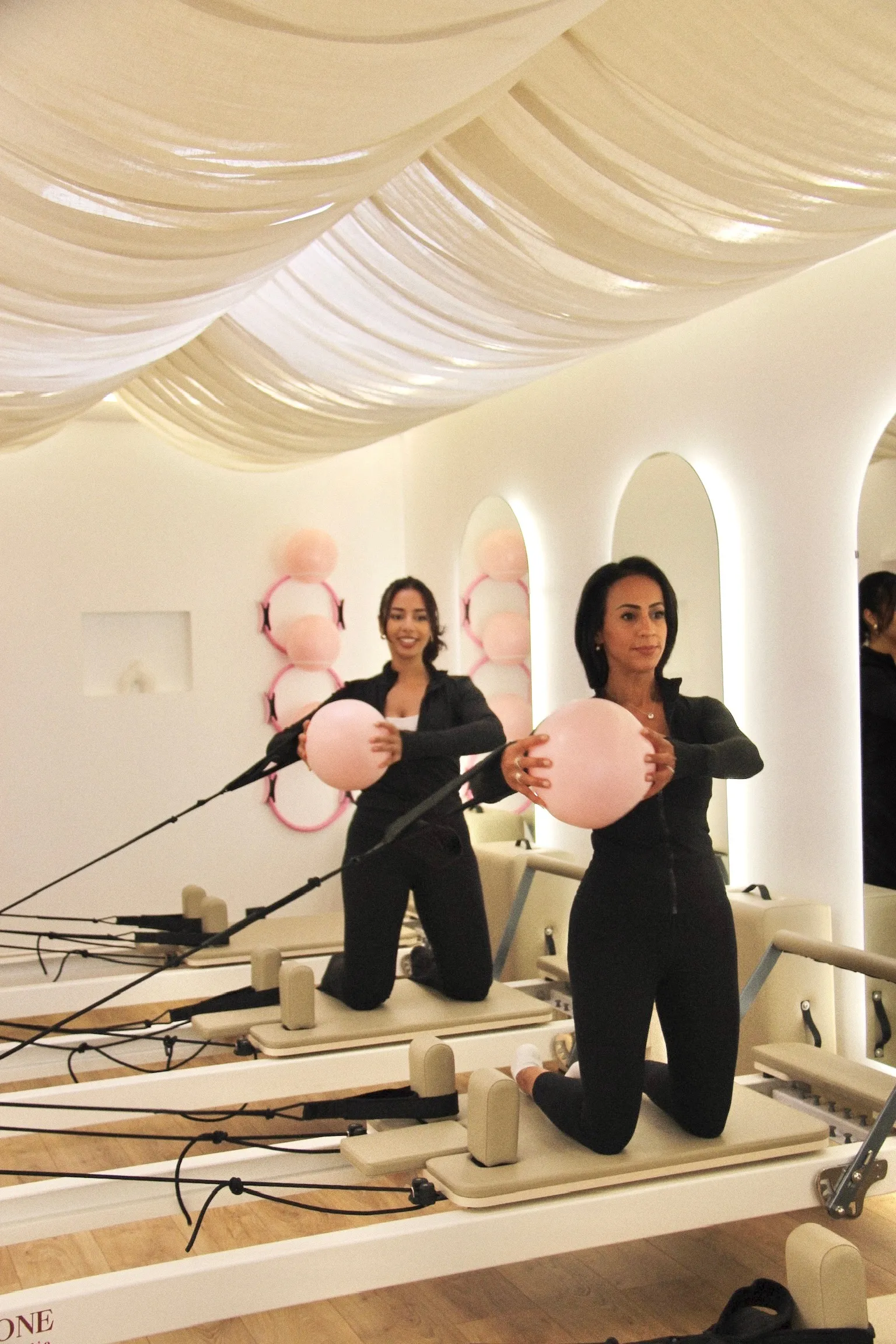 Les fondatrices à genoux sur deux reformers, un ballon rose entre les mains